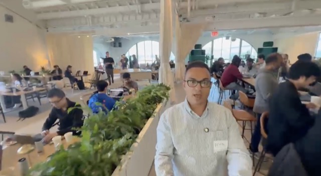 Aemal among hackathon participants at their laptops